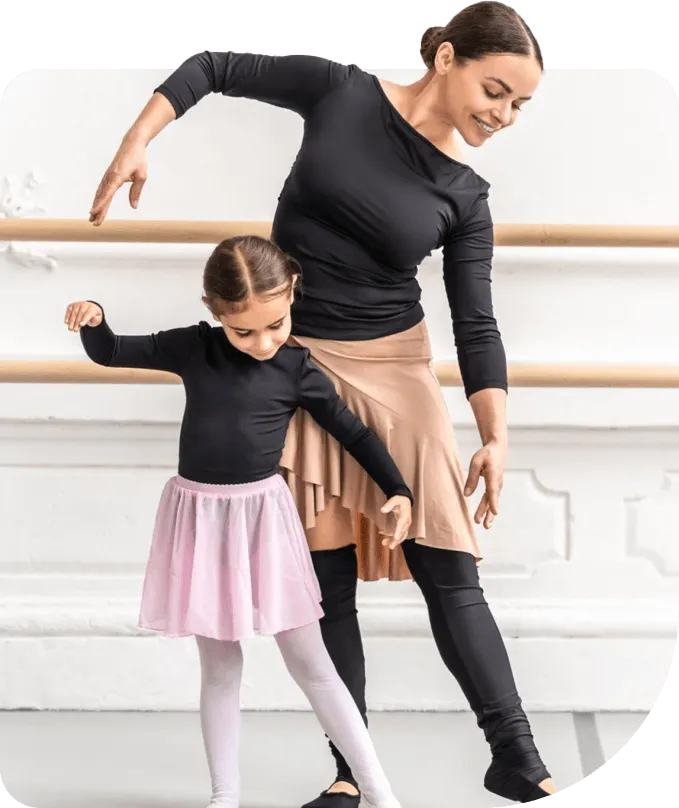 A ballet teacher guiding a young student at the barre